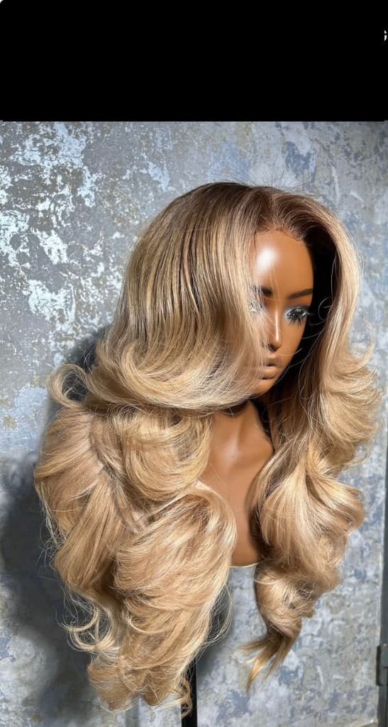 Body wave closure wig in multi-tonal blonde with voluminous curls on a mannequin